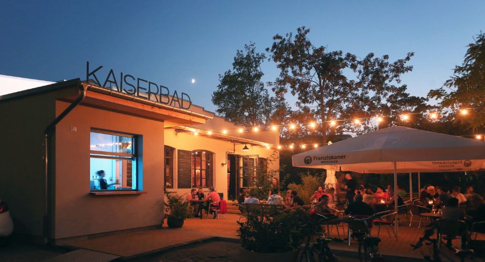Außenansicht KAISERBAD Leipzig bei Abenddämmerung mit Terrasse und Lichterketten
